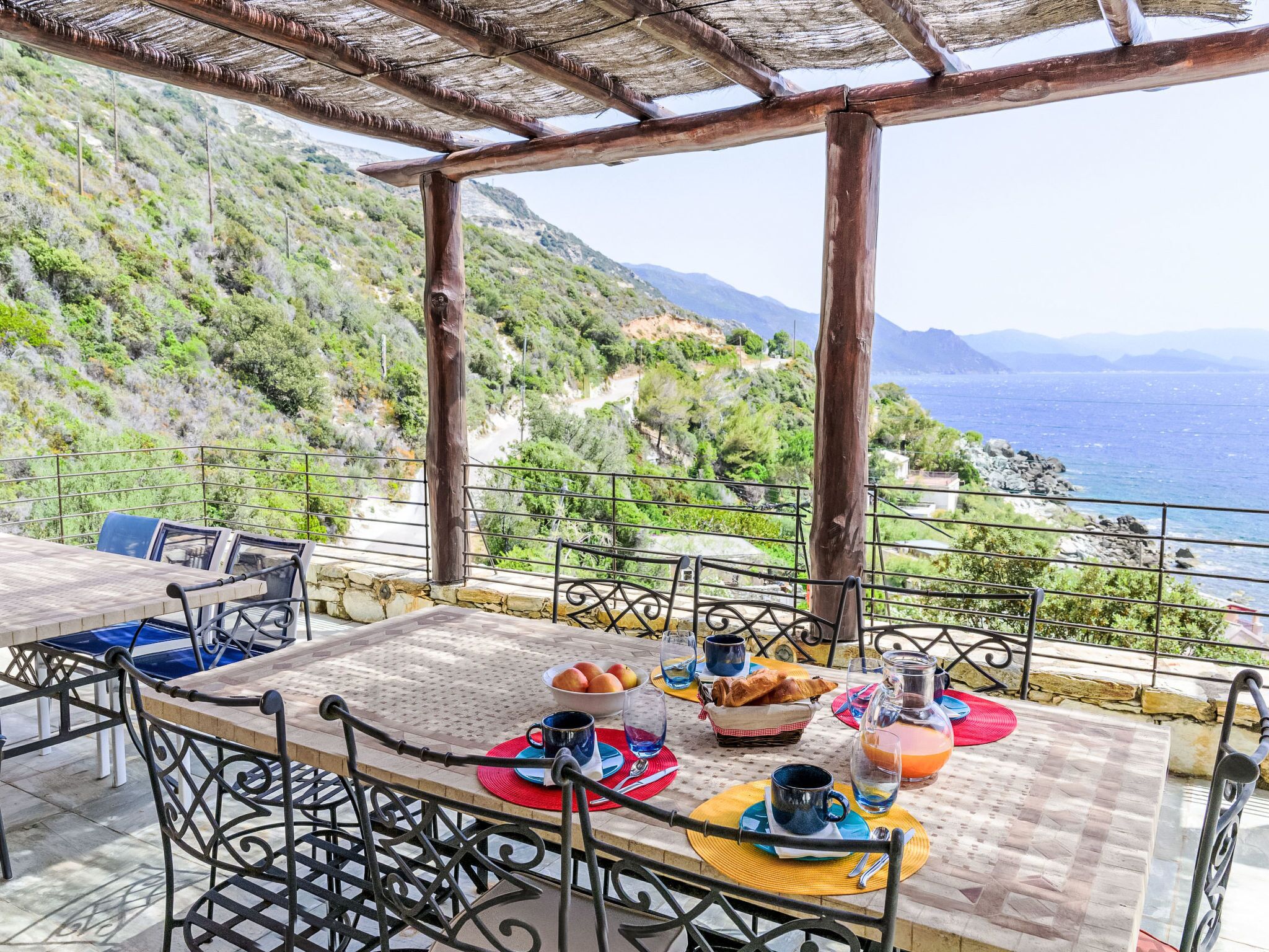 Mesa con alimentos para el desayuno, con vista a un paisaje costero.