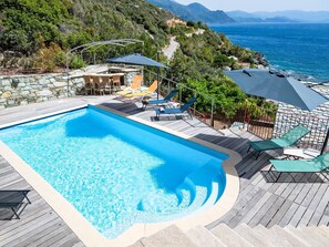 A swimming pool with a deck, lounge chairs, and umbrellas. - Kanelata by Interhome (Canari)