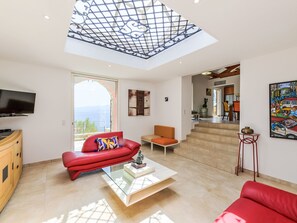 A spacious living room with a red sofa, a glass coffee table, and a TV. - Kanelata by Interhome (Canari)