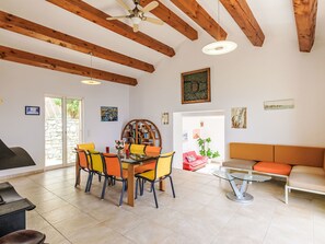 A dining area with a glass table and chairs, a sofa, and a ceiling fan. - Kanelata by Interhome (Canari)