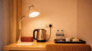 Un escritorio con lámpara, hervidor, botellas de agua y una bandeja con tazas.