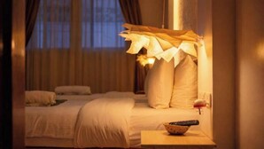 Una habitación de hotel con una cama, almohadas, una mesita de noche con un control remoto y una ventana con cortinas.