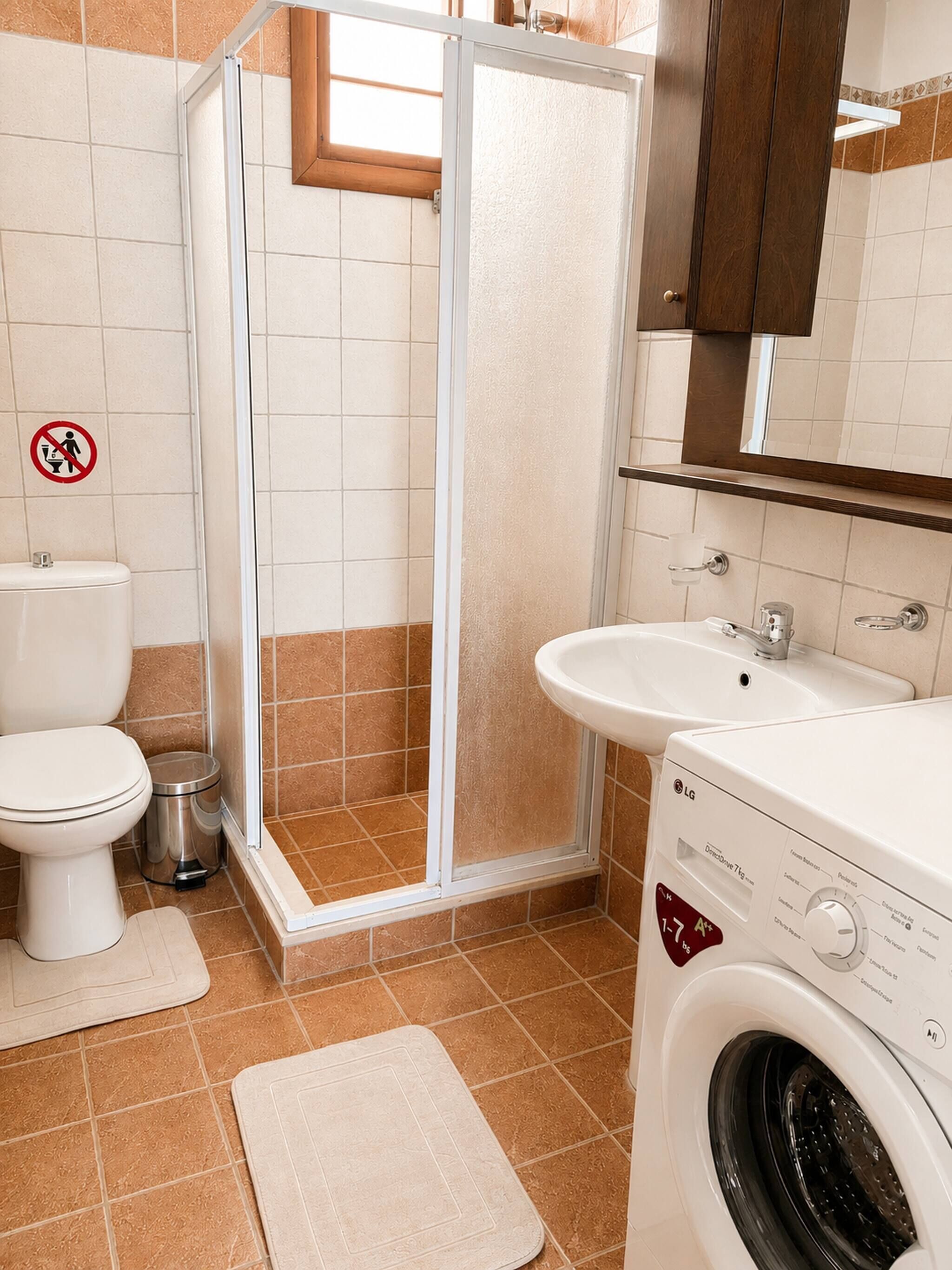 Une salle de bain équipée de toilettes, d’une douche, d’un lavabo et d’un lave-linge.