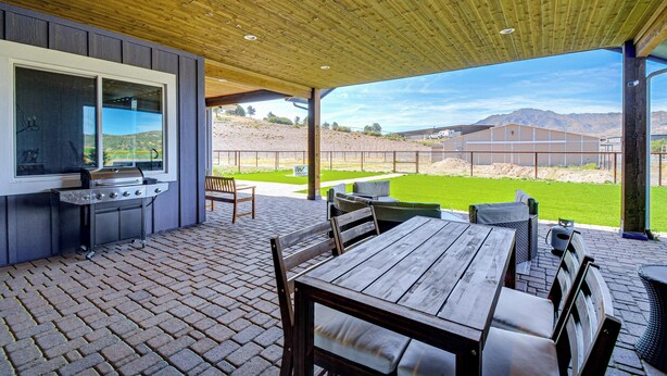 Een terras buiten met een barbecue, zitplaatsen en uitzicht op het landschap.