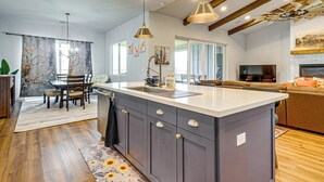 Een moderne keuken met een groot schiereiland, hanglampen en een eethoek met een tafel en stoelen.
