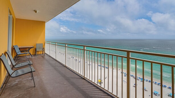 Een balkon met stoelen, een tafel en uitzicht op het strand en de zee.
