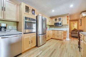 A modern kitchen with wooden cabinets, stainless steel appliances, and a wooden floor.