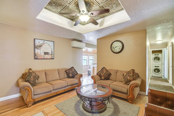 A living room with two sofas, a coffee table, a ceiling fan, and a clock on the wall.