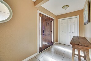A hallway with a wooden door, white double doors, and a small wooden table.