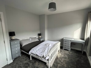 A bedroom with a bed, bedside tables, a desk, and a chair.