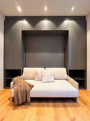 A modern room with a sofa, pillows, a knitted throw, and built-in shelving. - Apartment Places2be by Interhome (Schladming)