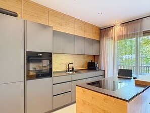Eine moderne Küche mit Backofen, Kaffeemaschine und einem großen Fenster mit Vorhängen.