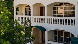 A multi-story building with balconies, large windows, and a tiled roof. - Beachside Getaway – Private 1-Bedroom Apartment with Pool (Puerto Plata)