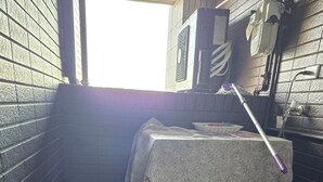 A corner of a room with a tiled floor, a table with a cloth, a bottle, and a mop. - Easy Inn Tainan (Monthly Lease) (Tainan City)