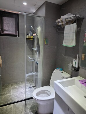 A modern bathroom with a glass-enclosed shower, a toilet, and a sink.