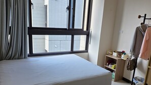 A bedroom with a bed, a window with blinds, a wardrobe, and a shelf with toiletries. - Easy Inn Tainan (Monthly Lease) (Tainan City)