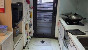 A compact kitchen with a microwave, stove, and cabinets. - Easy Inn Tainan (Monthly Lease) (Tainan City)