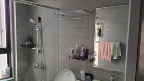 A modern bathroom with a glass shower enclosure, a toilet, a sink, and a mirror. - Easy Inn Tainan (Monthly Lease) (Tainan City)