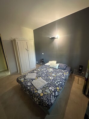 A bedroom with a bed, bedside tables, a wardrobe, and a wall-mounted light fixture.