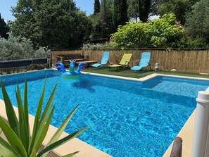 Une piscine avec un jouet flottant, entourĂ©e dâune terrasse en bois et de chaises.
