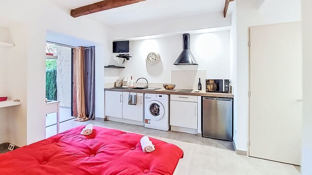 Una habitación funcional con cama, lavadora, microondas y lavabo.