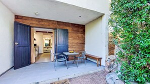 Entrada residencial con puerta de madera, un banco, una mesa y un felpudo.