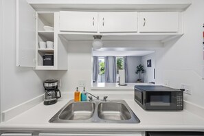 Eine moderne Küche mit einer Spüle, einer Kaffeemaschine, einer Mikrowelle und einem Schrank mit Kaffee.