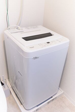 A compact, white, wall-mounted laundry machine with a control panel and a transparent door. - Zenith Nishinakanobu 2 (Shinagawa)