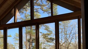 A covered outdoor seating area with a table and chairs, large windows, and a wooden lattice fence. - The Point At Lake Hartwell (Townville)