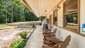 A covered outdoor seating area with wooden chairs and tables, a signboard, and a view of the surrounding forest. - The Point At Lake Hartwell (Townville)