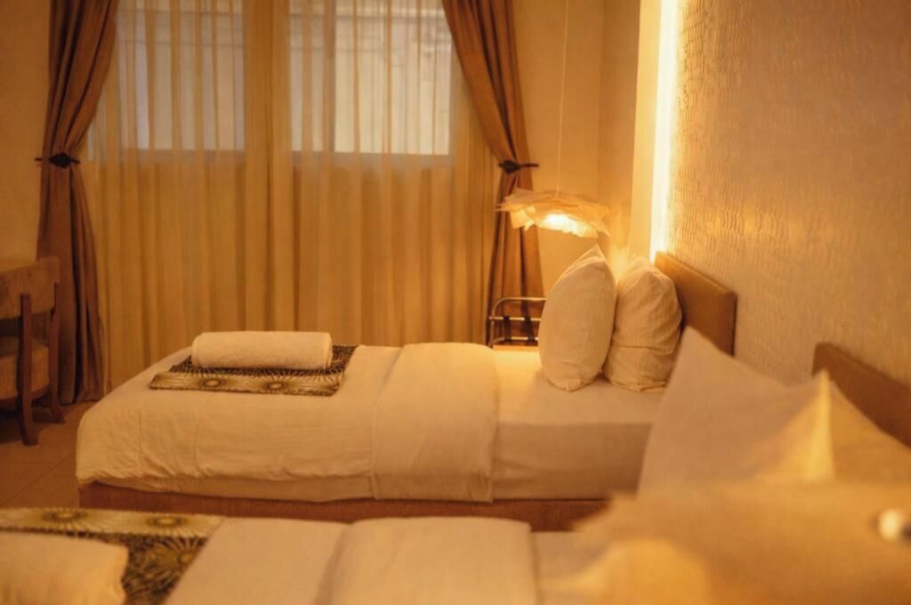 A hotel room with a bed, pillows, a bedside lamp, and curtains.