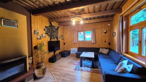 A wooden interior with a sofa, television, and a mounted animal hide. - Chalets Hana (Demänovská Dolina)