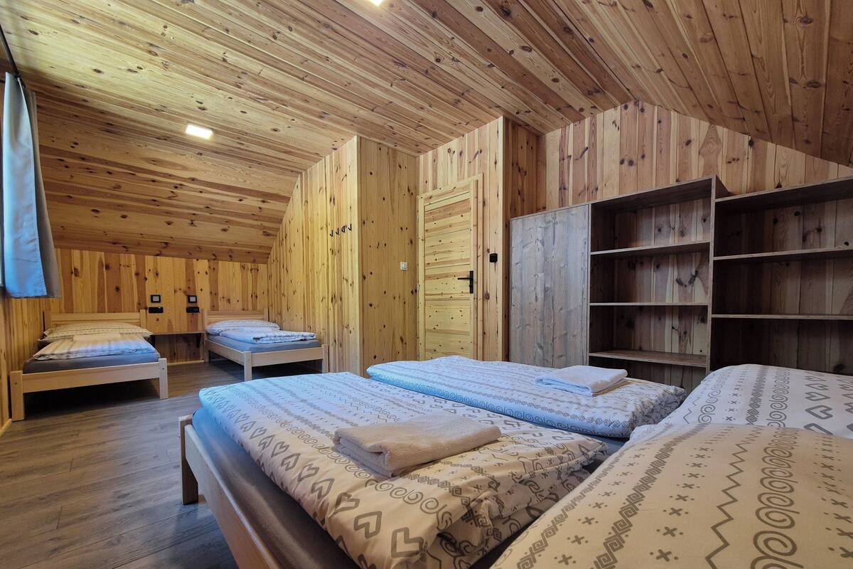 A wooden room with two beds, a wardrobe, and built-in shelves.