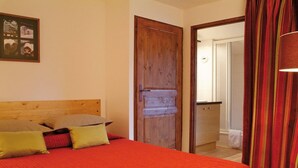 Un dormitorio con cabecera de madera, una cama con ropa de cama roja y una puerta que da al baño.