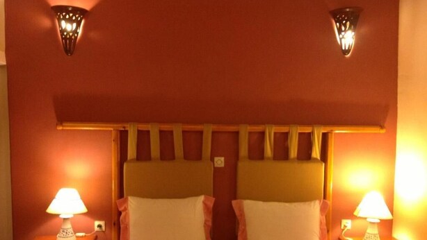 Una habitación de hotel con una cama, dos lámparas de noche y una lámpara fijada a la pared.