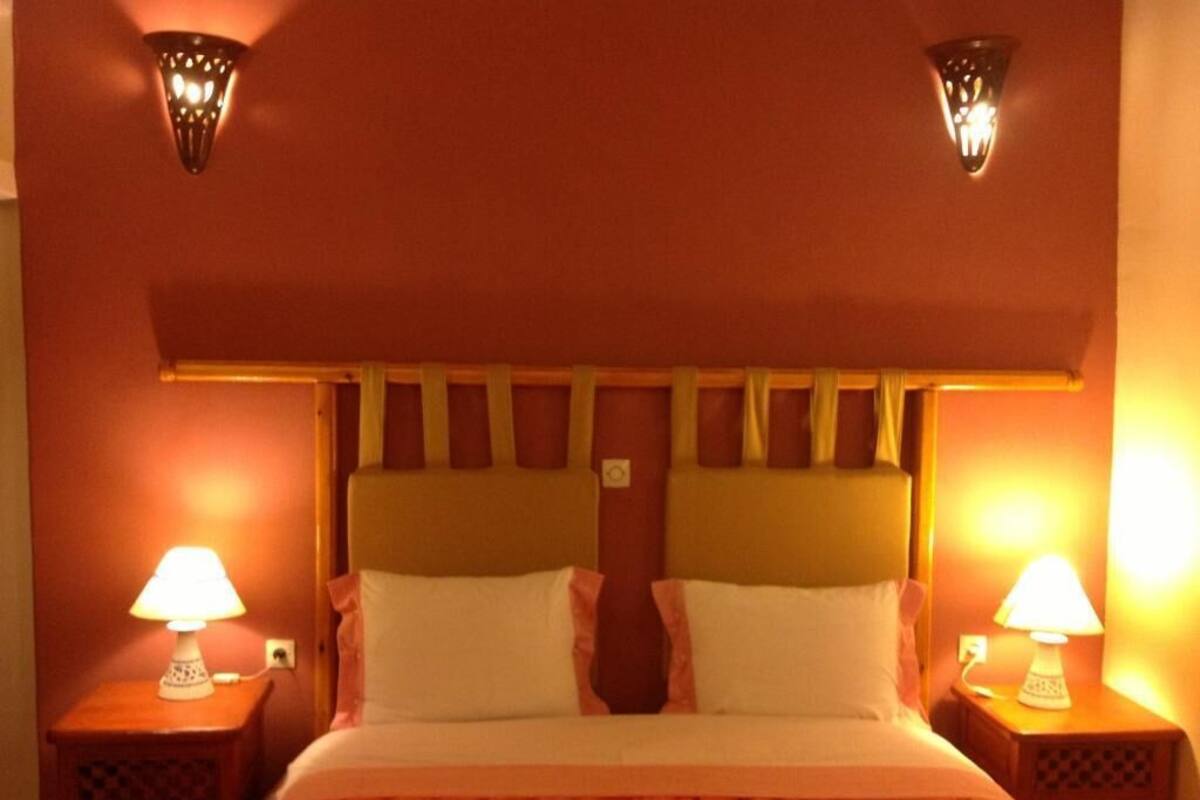 A hotel room with a bed, two bedside lamps, and a wall-mounted light fixture.
