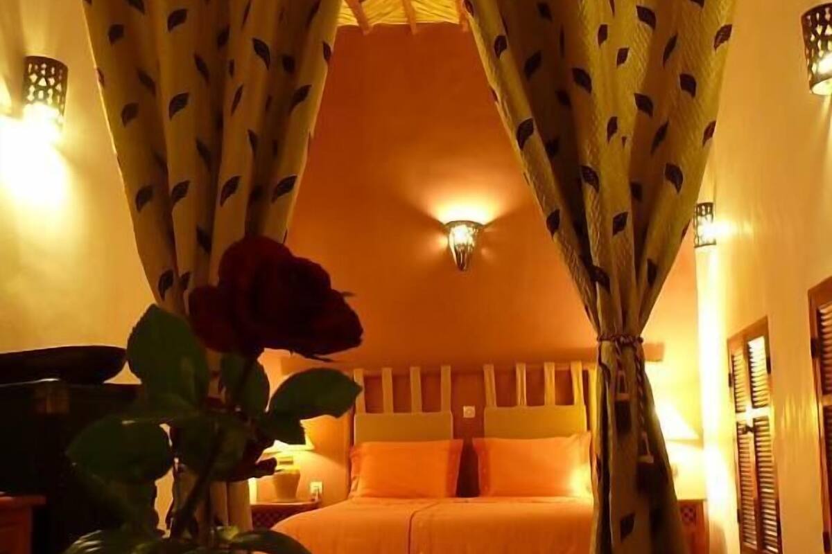 A room with a bed, a vase with a rose, and a water feature.