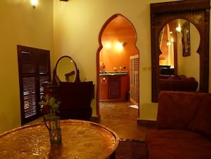 Un interior de estilo marroquí con un sofá, una mesa redonda y un espejo.