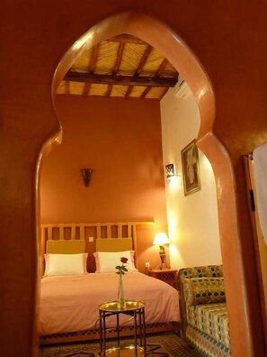 Una habitación de hotel con cama, mesita de noche, lámpara y una silla.
