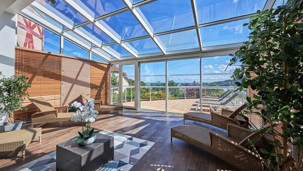 A spacious indoor area with a large glass ceiling, wicker furniture, and a view of the outdoors. - Sea View Houlgate Apartment for 4 (Houlgate)