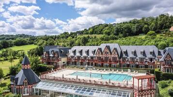 Un grand hôtel comprenant plusieurs bâtiments, une piscine et offrant une vue panoramique sur les collines environnantes.