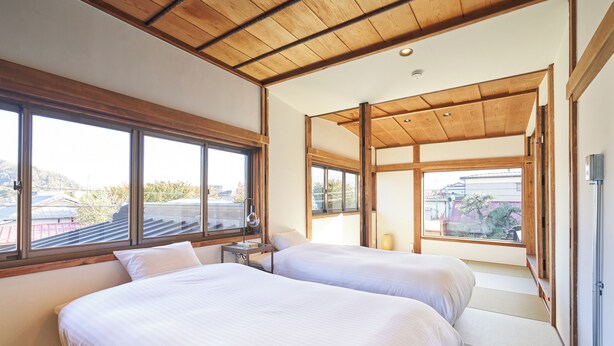Un dormitorio con dos camas, ventanas amplias y techo de madera.