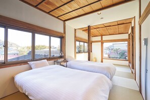 A bedroom with two beds, large windows, and a wooden ceiling.