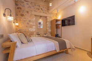 Ein Schlafzimmer mit Steinwand, einem Bett mit Holz-Kopfteil, einem Holzschrank, einem Wand-Fernseher und Wandleuchten.