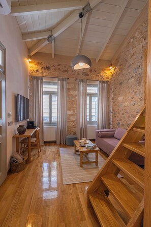 Ein gemütliches Wohnzimmer mit Holzböden, einer Couch, einem Couchtisch, einem Fernseher und einer Steinwand.