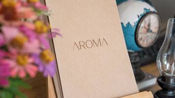 A brown paper bag with 'AROMA' printed on it, placed on a wooden stand.