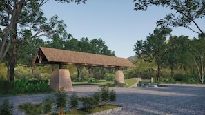 A stone bench with a thatched roof in a landscaped garden with trees and a pond. - Alagon Ecolodge Nam Cat Tien (Nam Cat Tien)