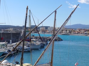 Ein Yachthafen mit vertäuten Booten, einem strahlend blauen Himmel und Gebäuden im Hintergrund.