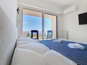 Ein Hotelzimmer mit Bett, Sessel, Fernseher und einem Balkon mit Blick.