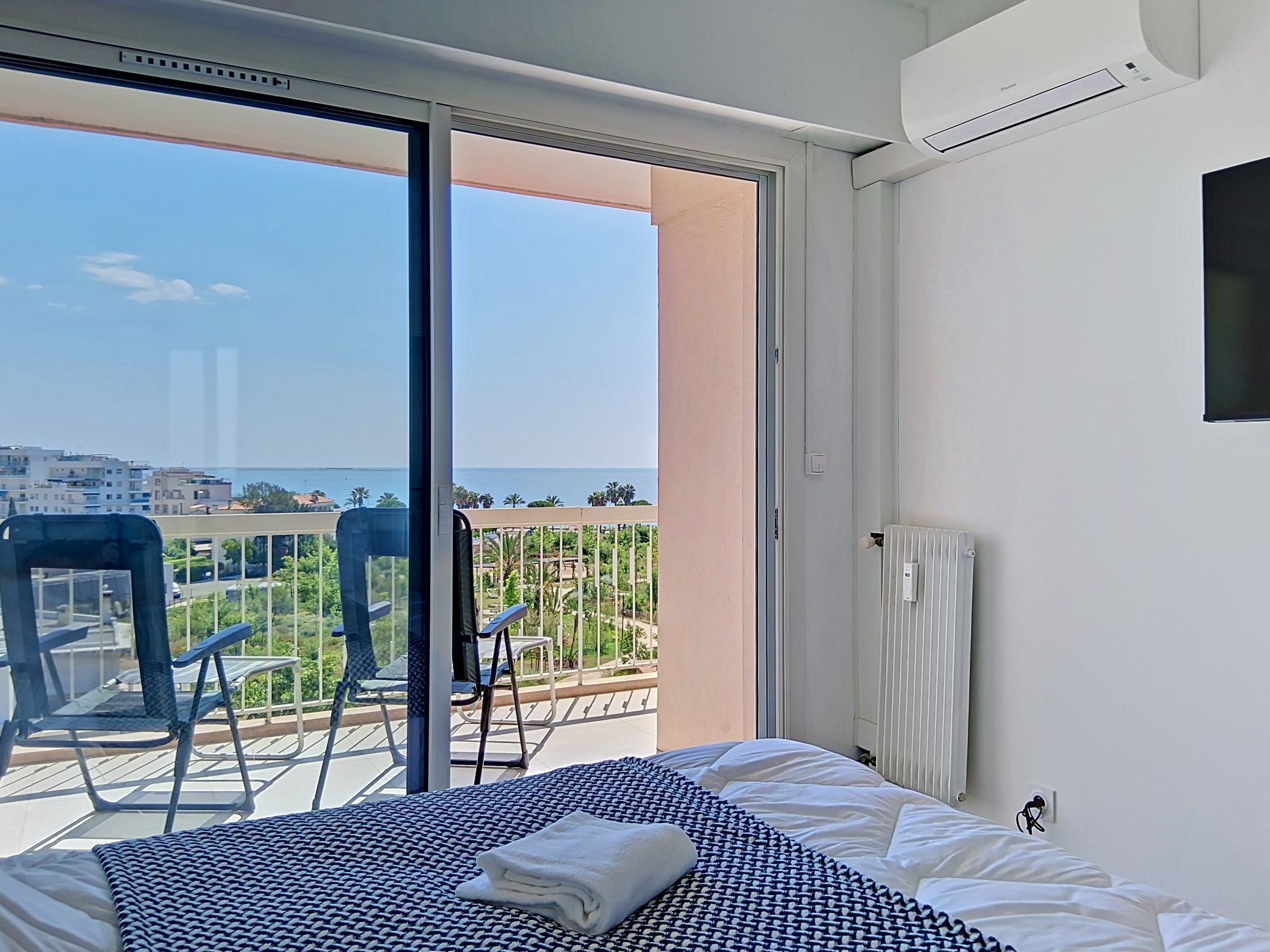 A hotel room with a bed, a window, and a view of the sea.